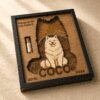 Close-up angled view of a personalized wooden pet memorial shadow box featuring a white dog portrait, layered rainbow bridge scenery, and a glass fur keepsake vial.