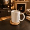 Warm lifestyle photograph of a white ceramic mug resting on a personalized cork pet memorial coaster on a dark wood coffee table beside a cozy fireplace and candlelit living room background.