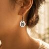 Custom Cat Portrait Earrings Lifestyle Close-Up Close-up lifestyle photo of a woman wearing a silver engraved cat portrait earring in warm golden natural light with soft blurred background.