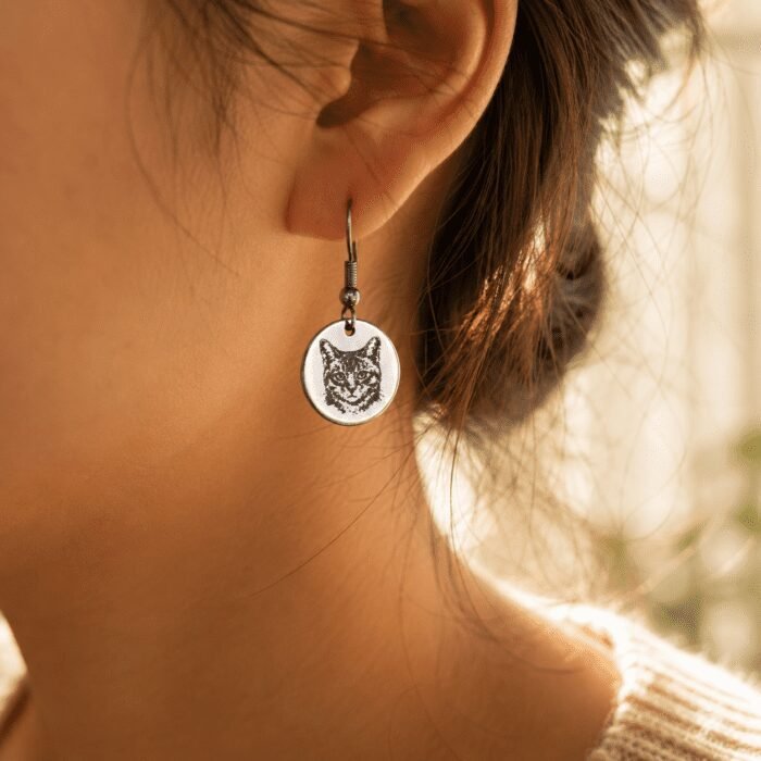 Custom Cat Portrait Earrings Lifestyle Close-Up Close-up lifestyle photo of a woman wearing a silver engraved cat portrait earring in warm golden natural light with soft blurred background.