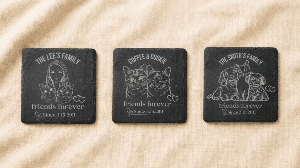 Three personalized engraved slate memorial coasters displayed side by side on cream linen fabric, featuring different family and pet combinations including a woman with two cats, two cats together, and two dogs with a cat.