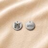 Custom Pet Portrait Charm – Front & Back Engraving Front and back view of a personalized engraved pet charm on beige linen fabric, featuring a custom cat portrait on one side and the year “2011” engraved on the reverse side.