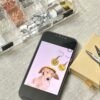 Workspace flat lay showing custom engraved pet earrings being designed from a dog photo on a smartphone, surrounded by jewelry-making tools and metal earring components.