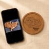 Comparison image showing a phone displaying the original cat photo beside a custom engraved cork coaster recreated from the same pet portrait.