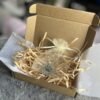 Open kraft gift box with tissue paper, shredded paper filler, and a personalized paw print keychain packaged inside a soft organza pouch.