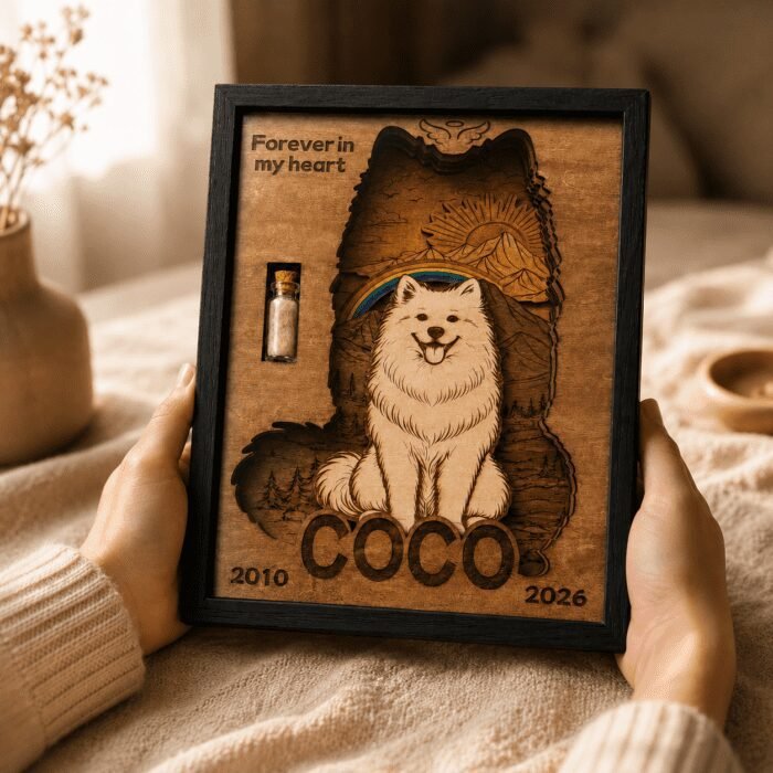 Warm lifestyle photo of a personalized wooden pet memorial shadow box being held in both hands on a cozy blanket in soft indoor lighting.