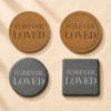 Comparison image showing four memorial coaster material and shape options, including round cork, engraved cork with border, round black slate, and square black slate, displayed on soft cream linen fabric.