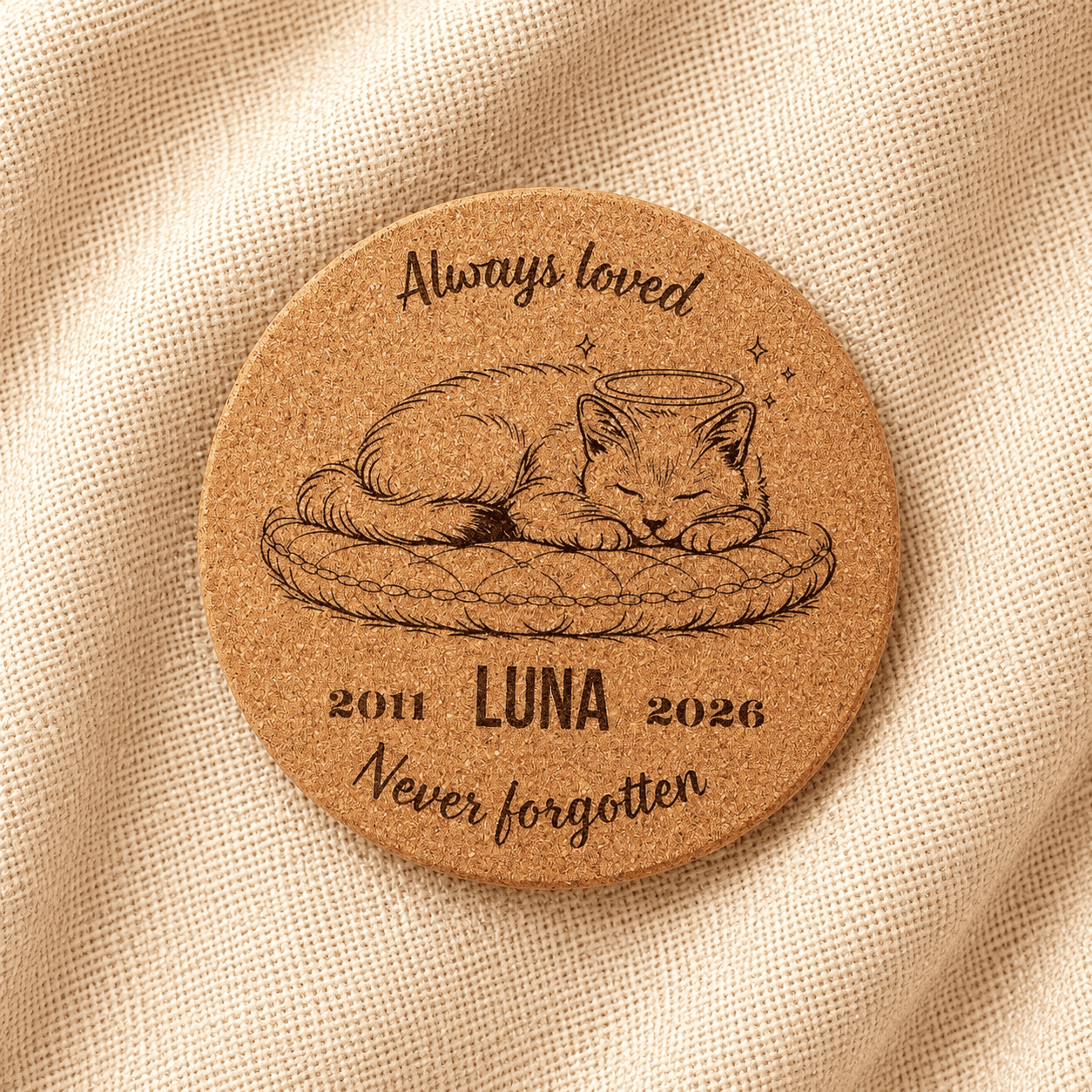 Top-down product photograph of a personalized round cork pet memorial coaster engraved with a sleeping cat illustration, the name Luna, memorial years 2011–2026, and the phrase “Never forgotten,” displayed on soft cream linen fabric.