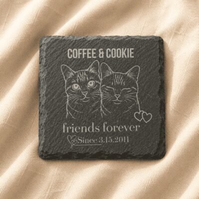 Personalized engraved square slate pet memorial coaster featuring custom cat portrait artwork, family name engraving, and commemorative text displayed on soft cream linen fabric.