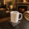 Personalized Memorial Coaster in a Cozy Home Setting Warm lifestyle photograph of a white mug resting on a personalized slate memorial coaster beside a fireplace in a cozy living room setting.