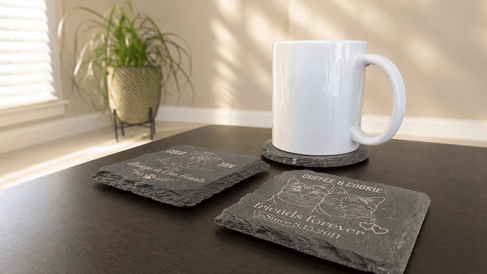 Warm indoor lifestyle scene featuring personalized engraved slate coasters with pet portraits and memorial messages beside a white coffee mug on a dark wooden table with soft sunlight streaming through a nearby window.