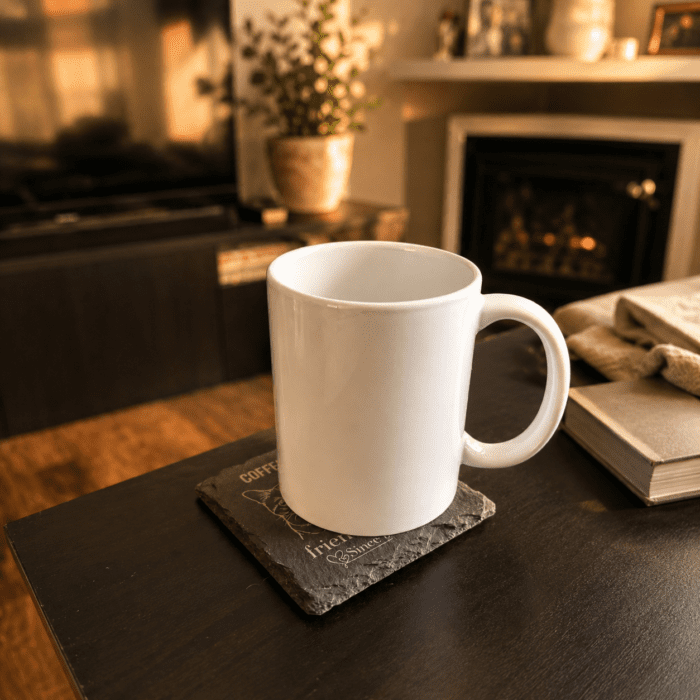 Personalized Slate Pet Memorial Coaster in Cozy Home Setting Personalized engraved slate pet memorial coaster used as a mug coaster on a cozy living room coffee table beside a fireplace in warm ambient lighting.