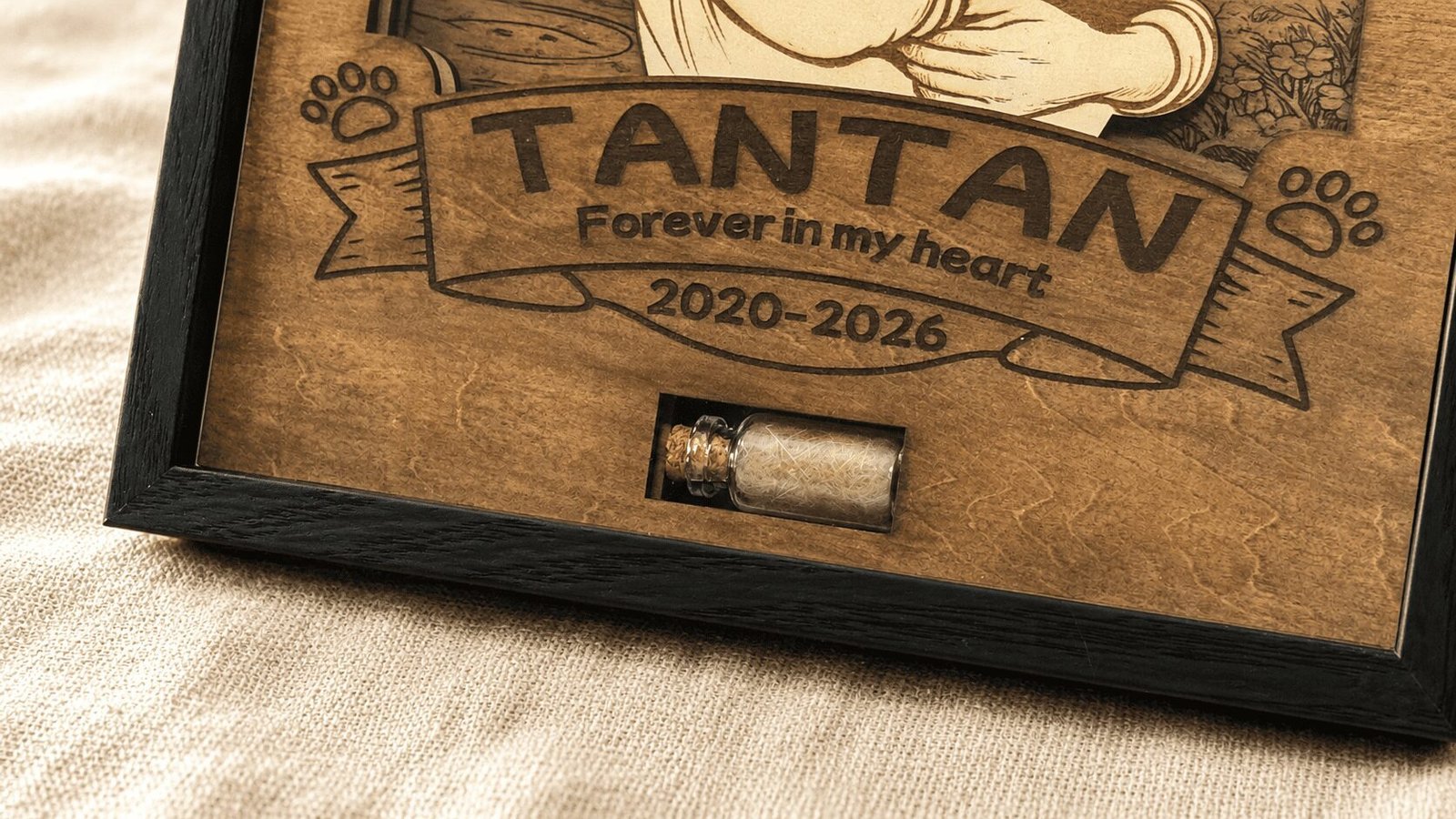 Close-up detail photo of a personalized wooden pet memorial shadow box showing engraved pet name, memorial dates, and a small glass keepsake vial filled with preserved pet fur.
