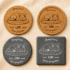 Comparison of personalized pet memorial coaster options in cork and slate materials with round and square shapes on neutral linen fabric.