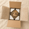 Open shipping box showing a personalized wooden pet memorial shadow box securely packaged with protective corner guards and bubble wrap.