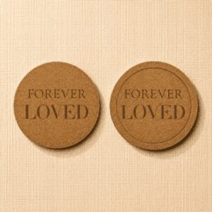 Comparison of two round cork pet memorial coasters featuring the engraved phrase “Forever Loved,” showcasing flat-edge and recessed-edge designs on a neutral linen background.
