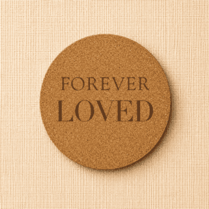 Round cork pet memorial coaster engraved with the words “Forever Loved” on a neutral linen background, a natural remembrance keepsake for honoring a beloved dog or cat.