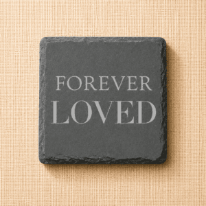 Square slate pet memorial coaster engraved with the words “Forever Loved” on a neutral linen background, a timeless remembrance keepsake for honoring a beloved dog or cat.