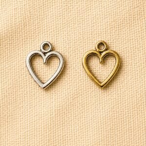 Silver and gold heart-shaped memorial charm pendants displayed on a beige linen background, designed for pet memorial jewelry, keepsakes, and remembrance accessories.