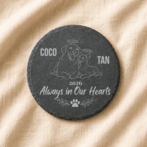Personalized pet memorial round slate coaster featuring engraved portraits of a dog and cat, custom pet names, memorial year, and the quote “Always in Our Hearts,” displayed on a soft linen background.