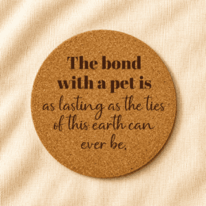 Round cork coaster featuring an engraved sentimental pet quote in mixed serif and script typography on a warm cream linen background.