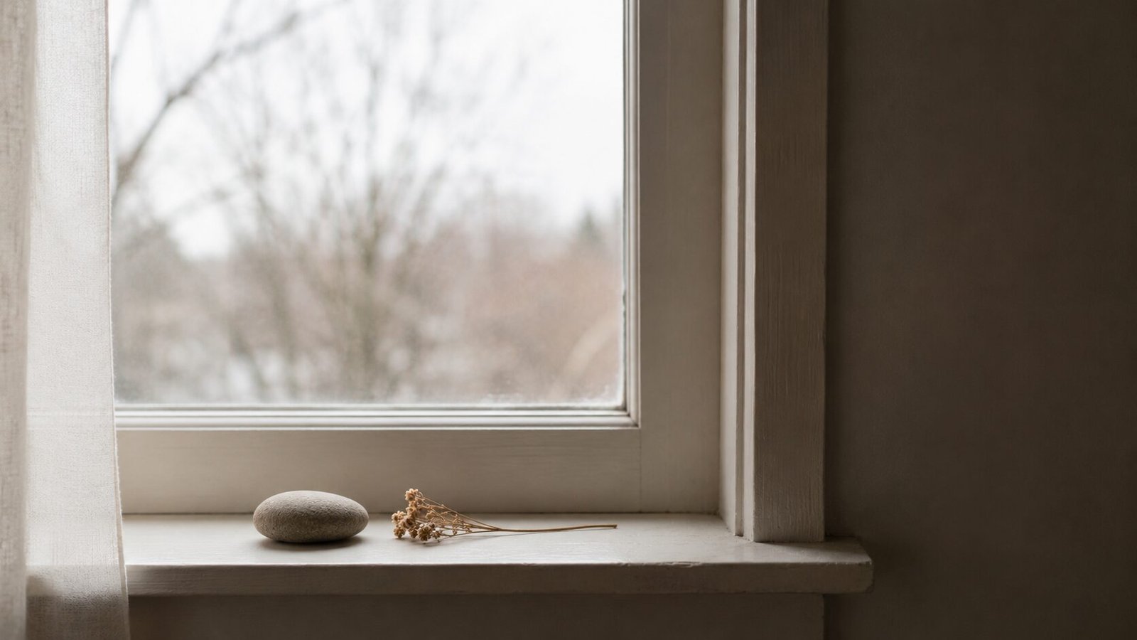 Minimal windowsill scene with a smooth stone and dried flowers beside a softly lit window, symbolizing peace, remembrance, acceptance, and gentle healing after pet loss.