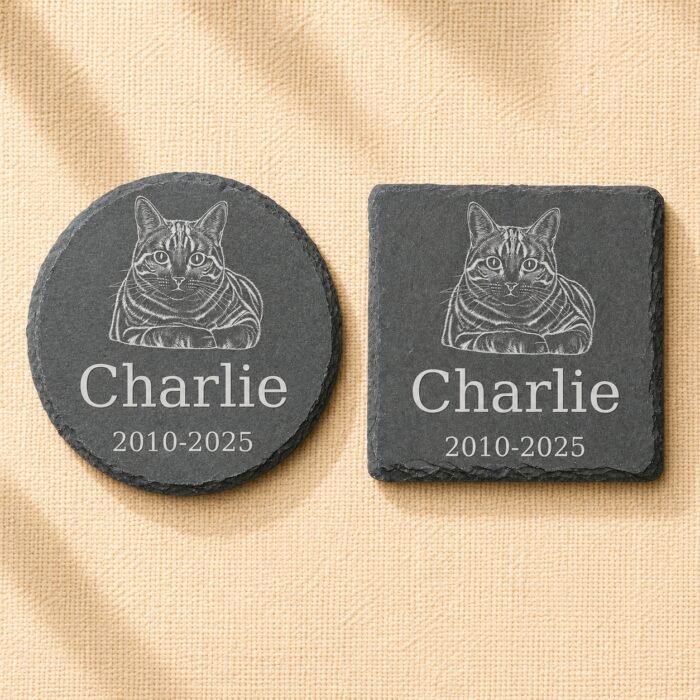Comparison photograph of round and square personalized pet memorial slate coasters engraved with a detailed cat portrait, pet name Charlie, and memorial dates on neutral woven fabric.