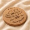 Personalized Cork Pet Memorial Coaster with Sleeping Cat Design Close-up angled photograph of a personalized round cork pet memorial coaster engraved with a sleeping cat illustration, the name Luna, memorial years 2011–2026, and the phrase “Never forgotten,” displayed on soft neutral linen fabric.